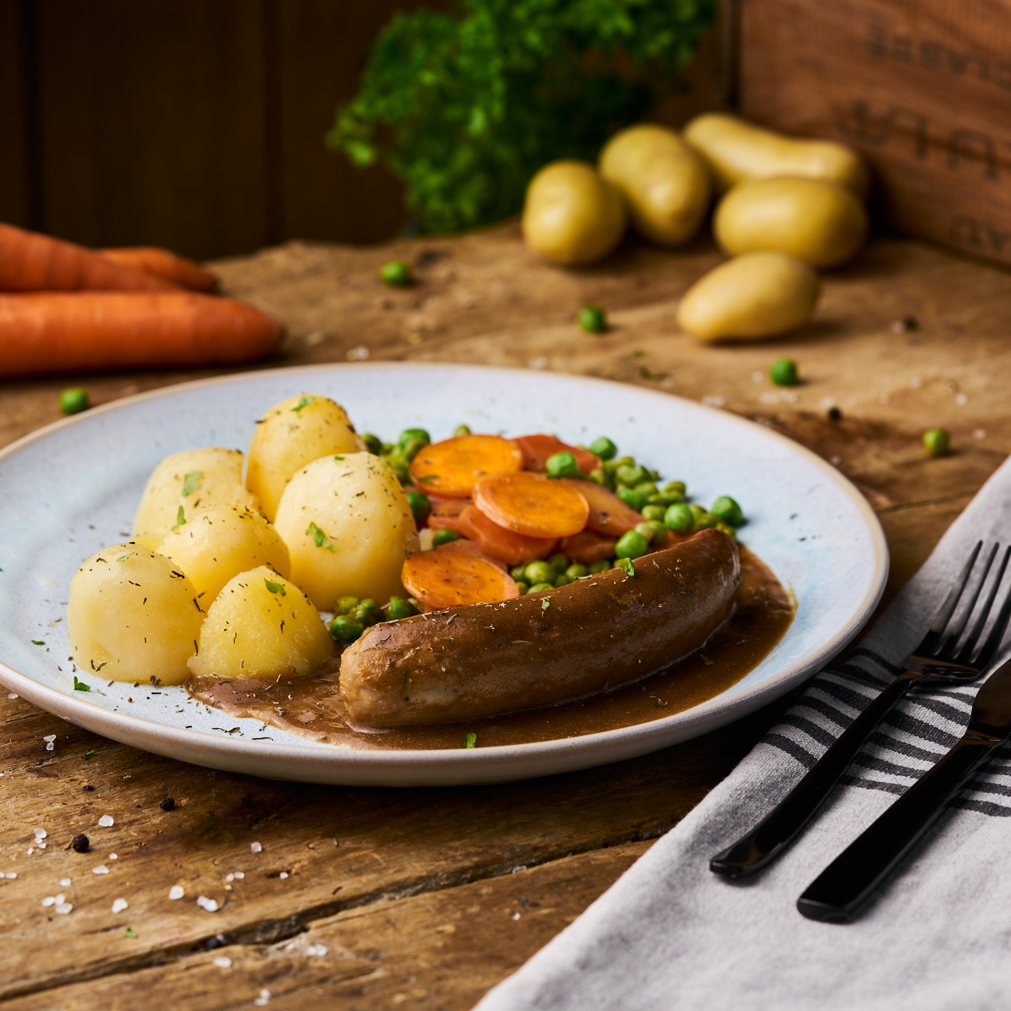Bratwurst in Sauce an Erbsen-Möhrengemüse und Butterkartoffeln als Fertiggericht